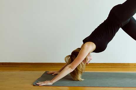 Woman practicing yoga in downward dog pose on a yoga mat indoors.