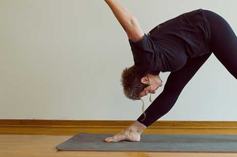 Person performing a forward bend yoga pose on a mat.